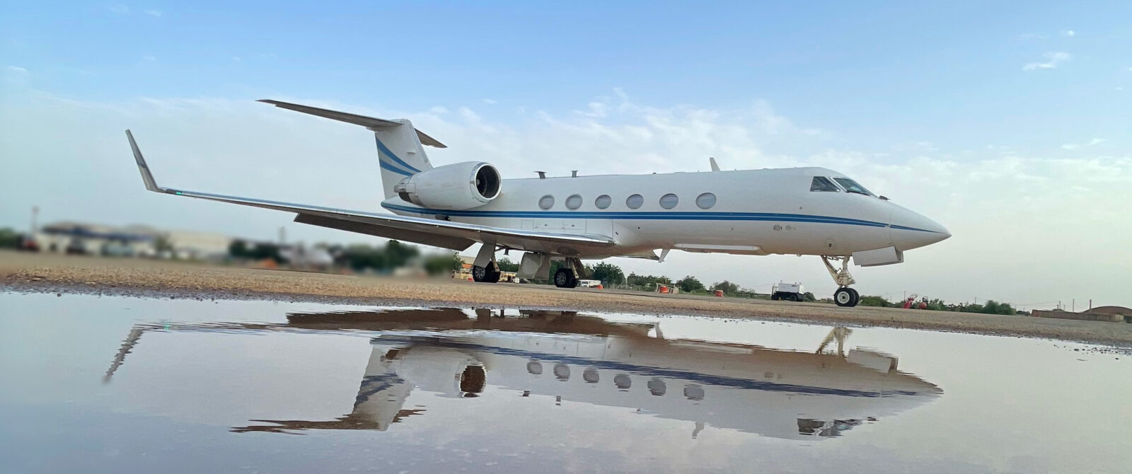 Private jet on a runway, reflected in pooled water